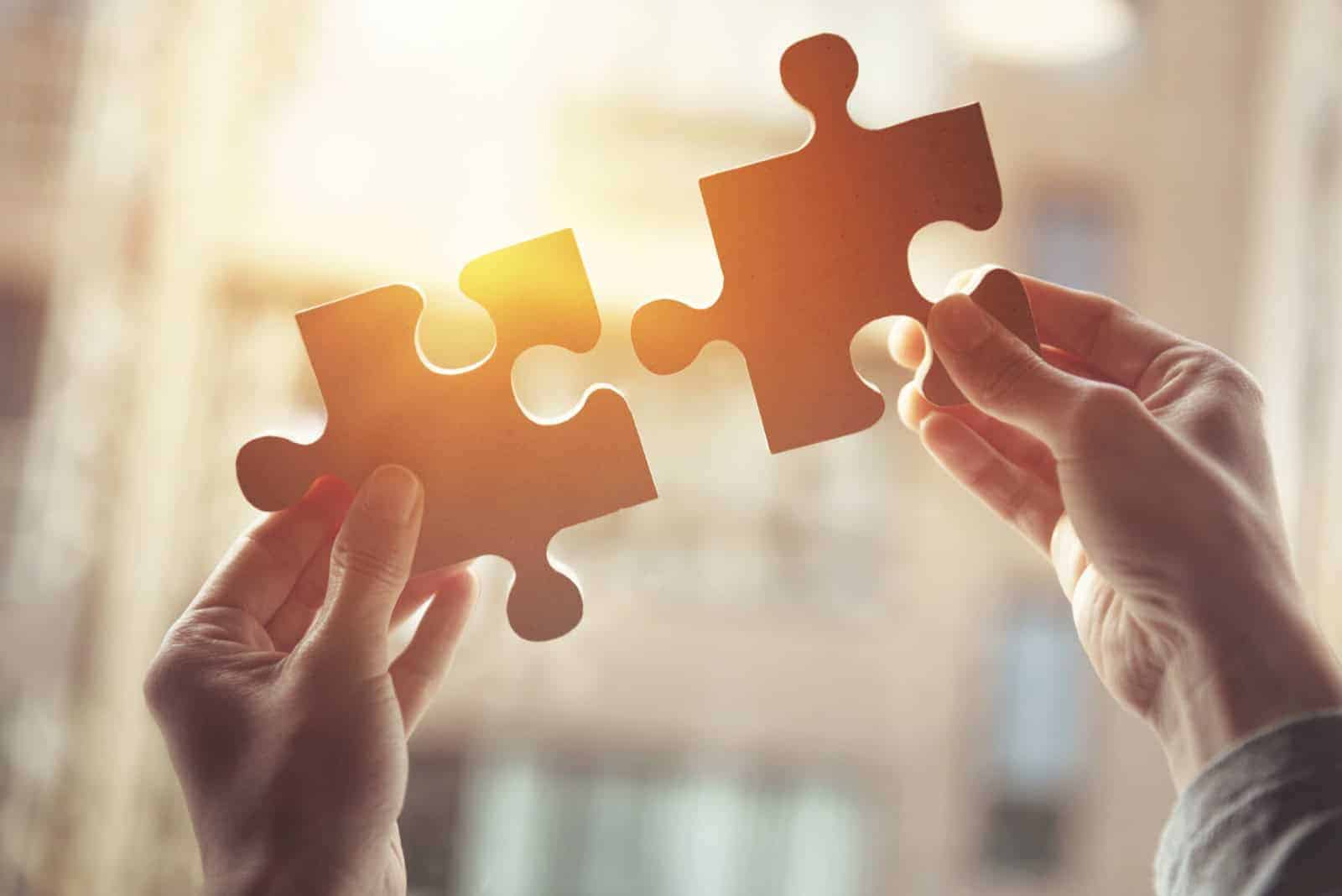Zwei Hände führen zwei Puzzleteile zusammen